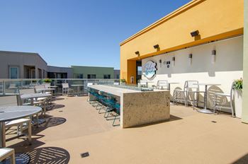 a patio with tables and chairs and a bar on the side of a building